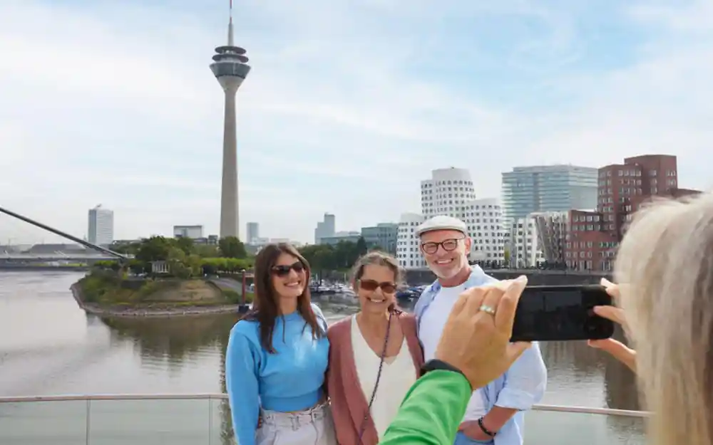 Group posing by river with TV tower and cityscape