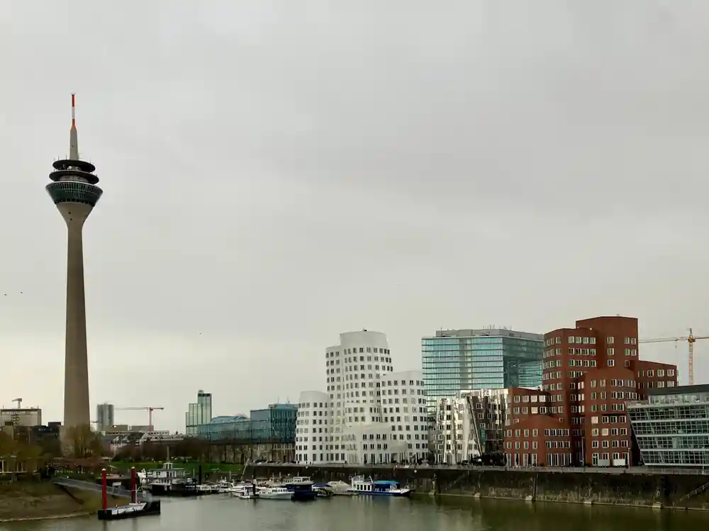 TV tower and cityscape beside river with boats