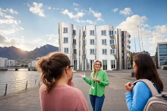 Woman in green jacket gesturing to group in courtyard